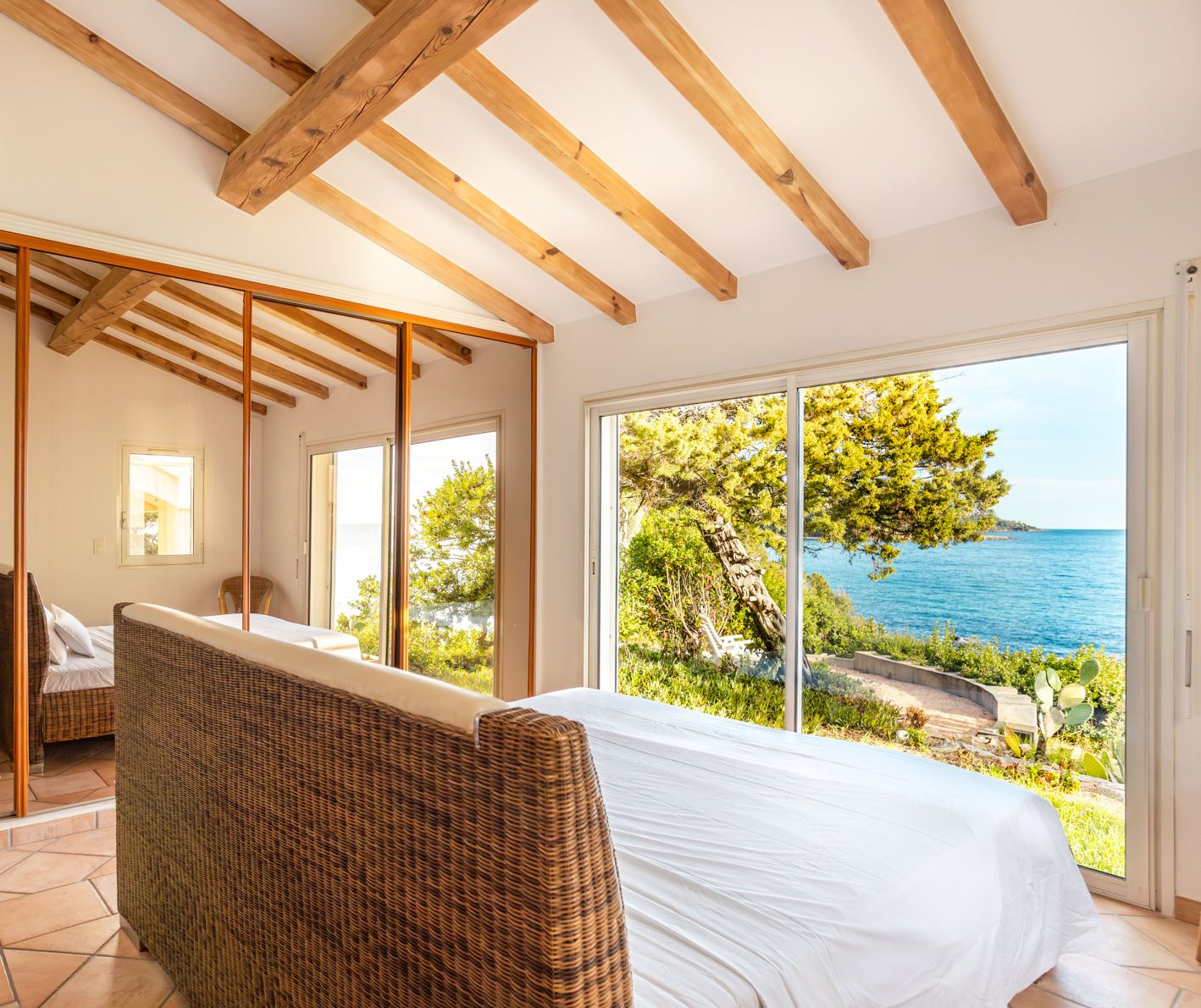 Schlafzimmer mit Rattanbett und Blick auf die Bucht